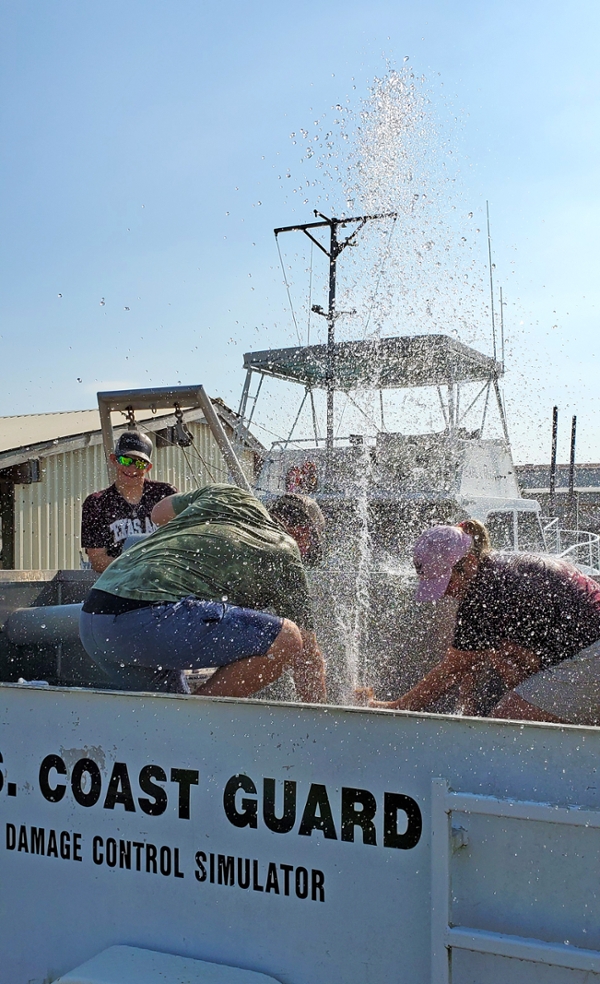 Water sprays high into the air Friday morning as MESSO and vessel operations staff and crew members work to stop a simulated leak during training drills on the U.S. Coast Guard’s damage control simulator.