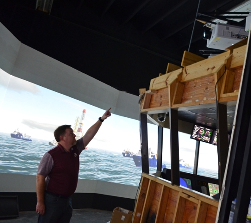 Texas A&M University at Galveston Campus Technical Lab Coordinator Patrick Zimmer points to the new projectors installed in the full-bridge ship simulator, greatly enhancing the resolution and overall experience for Texas A&M Maritime Academy cadets as they learn ship-handling drills and maneuvers. 