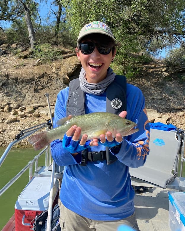 Chris Pryor holding a fish while collecting field data in Comfort, Texas